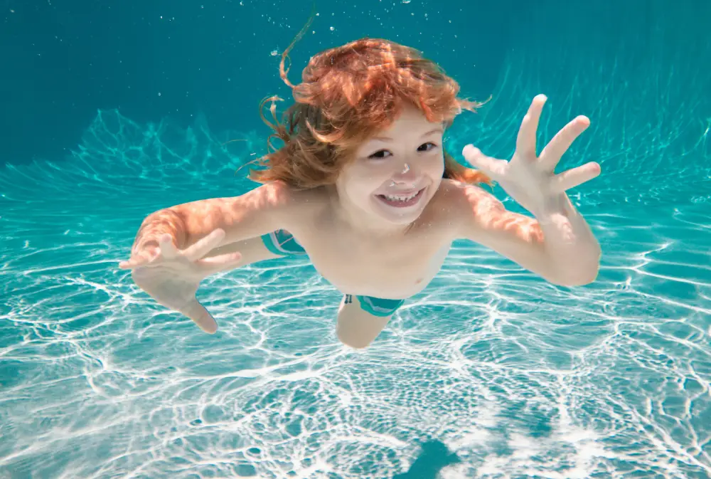 Child underwater. Funny face portrait of child boy swimming and diving underwater with fun in pool.
