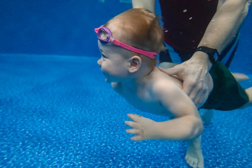 Baby boy dives underwater in the pool with pleasure