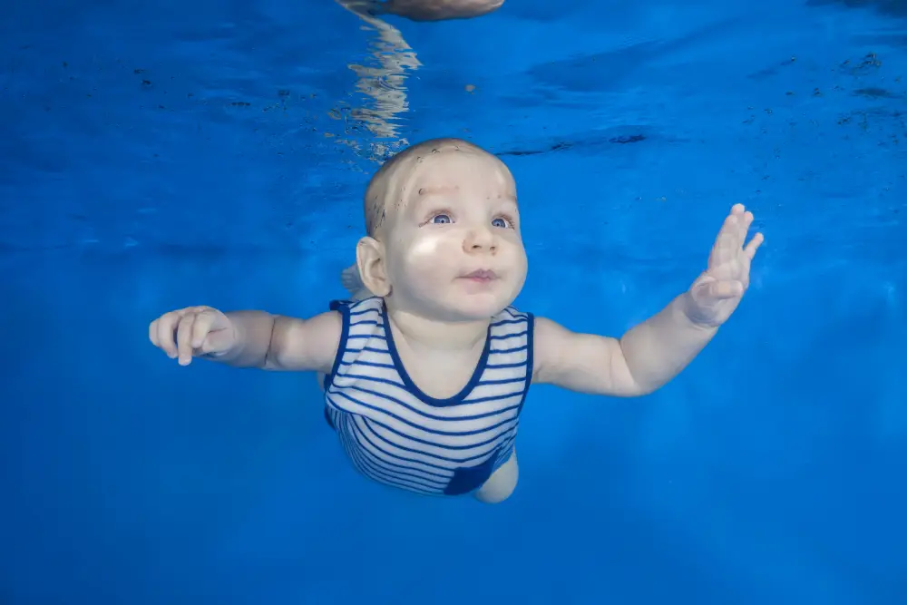 Little boy in a striped suit swim underwater on a blue water background. Healthy family lifestyle and children water sports activity. Child development, disease prevention