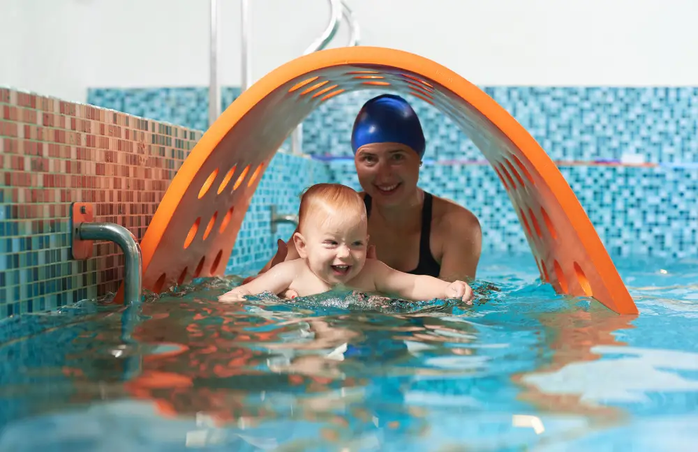 Playful active training in swimming pool. Little cute boy is learning how to float with his supportive mother. Concept of healthy family