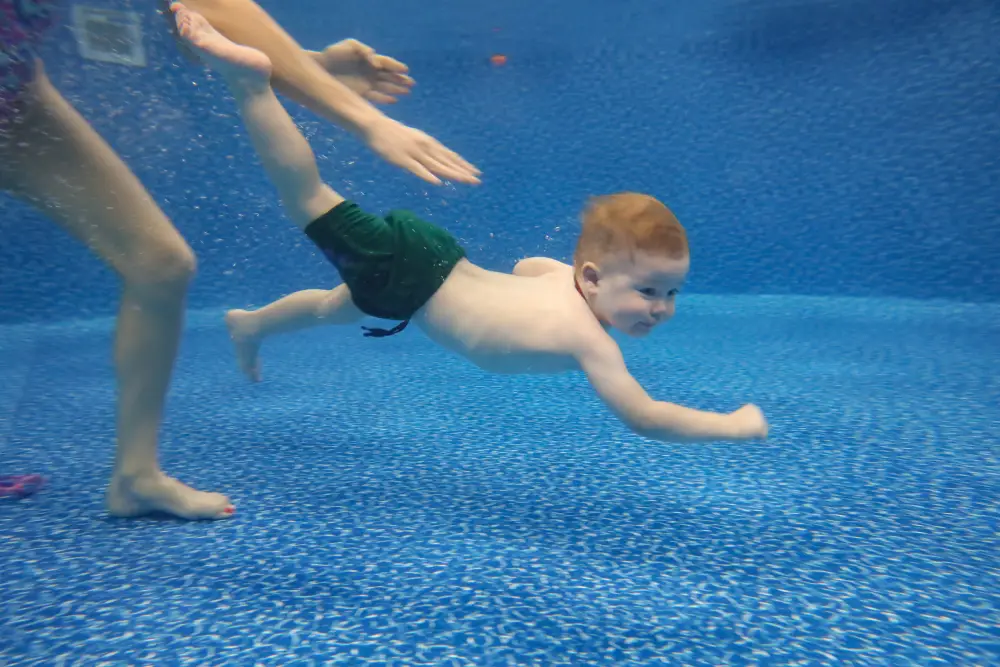 Baby boy dives underwater in the pool with pleasure