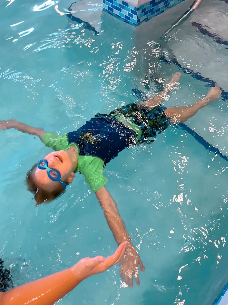 a boy is learning how to swim with a bathing strap